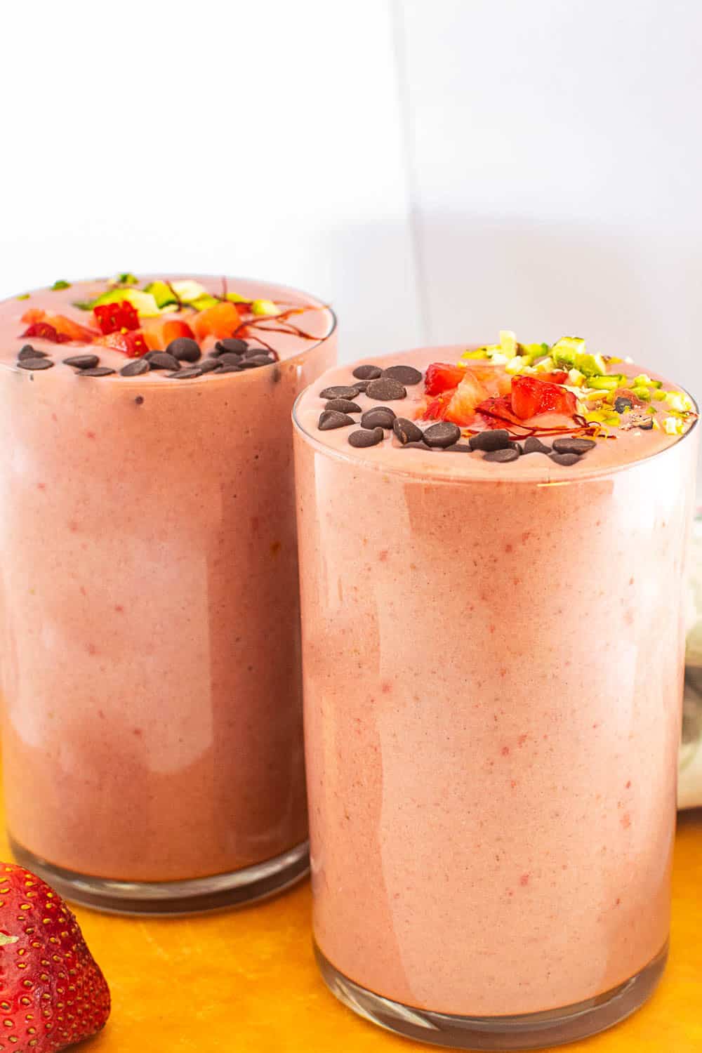 a front view of served strawberry lassi in serving glasses and with garnishes.