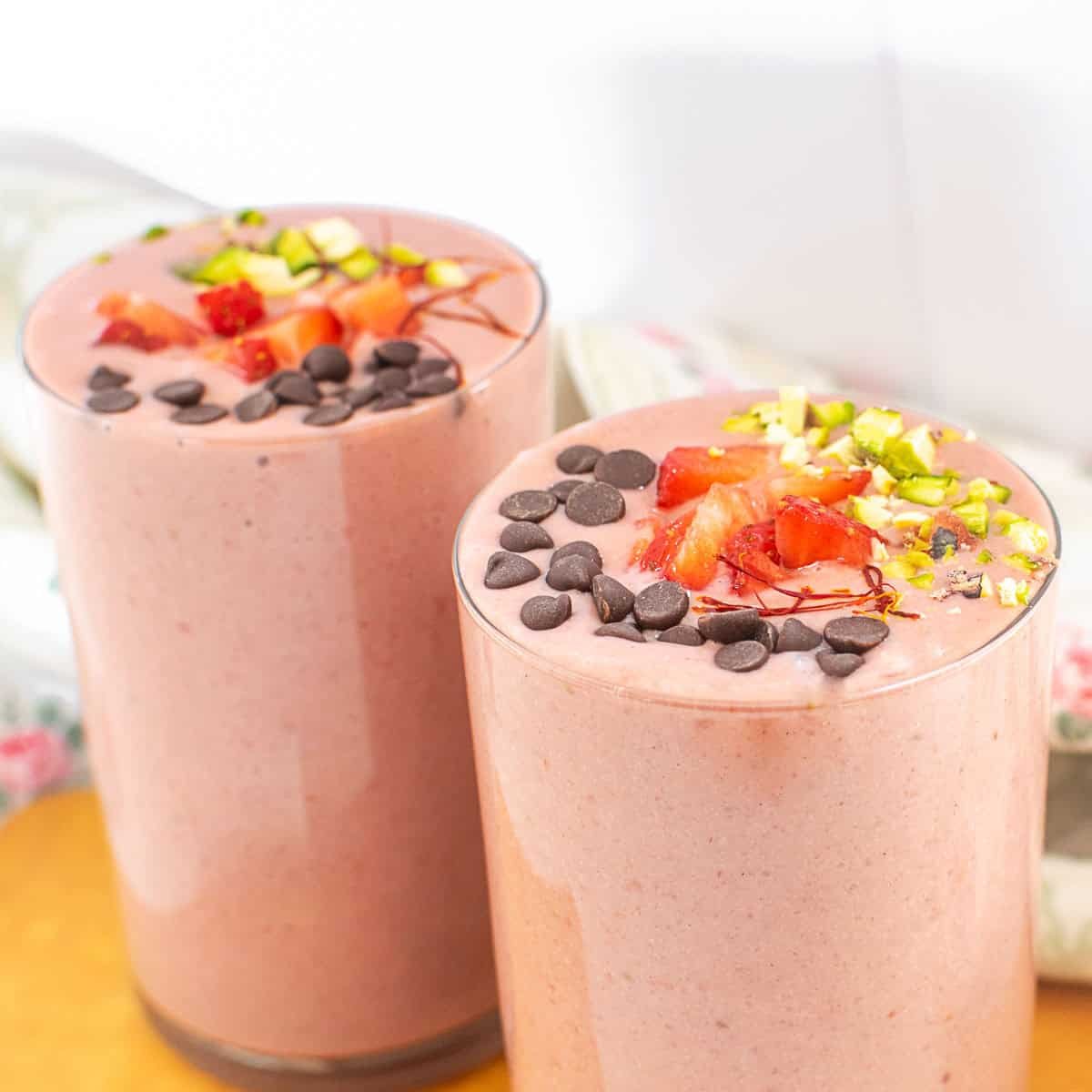 a close up view of served strawberry lassi with its garnishes.