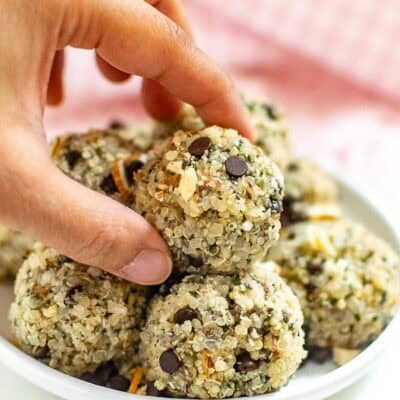 a hand placing quinoa energy balls on its stack.