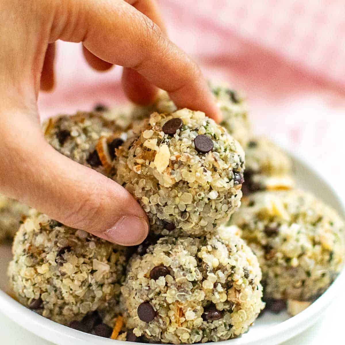 a hand placing quinoa energy balls on its stack.
